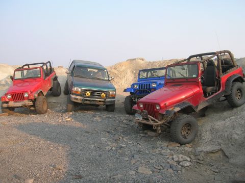 1996 Ford Bronco - Multiple off-road vehicles are positioned on a challenging, rocky landscape.
