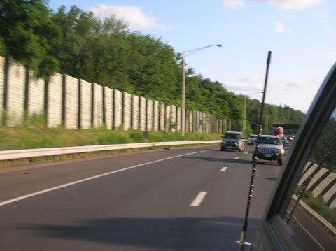 1996 Ford Bronco - Driving on a highway with multiple vehicles and a sound barrier along the side.