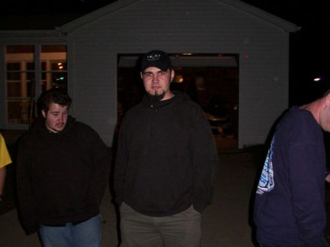 1998 Ford Taurus - Three men are gathered outside a garage at night, with one man in the center wearing a black baseball cap.