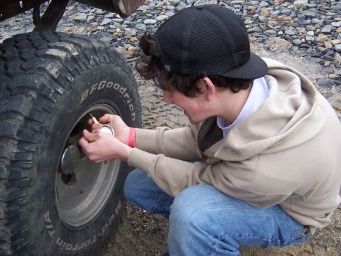 1996 Ford Bronco - A person uses a tire pressure gauge on a BFGoodrich Mud-Terrain tire.