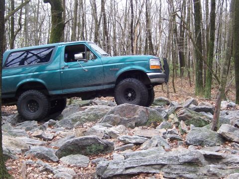 1996 Ford Bronco - Green 1996 Ford Bronco tackles a challenging rocky terrain in the woods.
