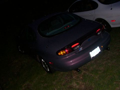 1998 Ford Taurus - A purple 1998 Ford Taurus is parked on grass next to a white car.