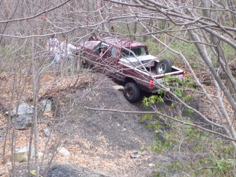 1996 Ford Bronco - Maroon 1996 Ford Bronco navigating a challenging off-road terrain with assistance from onlookers.