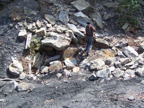 1996 Ford Bronco - A person stands amidst a pile of rocks and coal on a hillside.