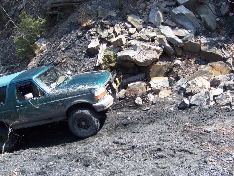 1996 Ford Bronco - 1996 Ford Bronco navigating a challenging off-road terrain with steep, rocky inclines.