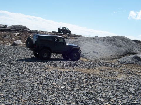 1996 Ford Bronco - Off-road vehicles traverse a challenging rocky terrain on a clear day.
