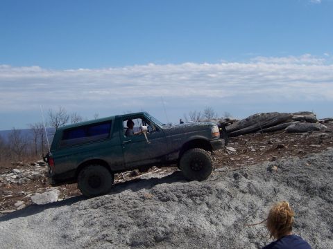 1996 Ford Bronco - This 1996 Ford Bronco is navigating a challenging off-road terrain with large rocks and loose gravel.