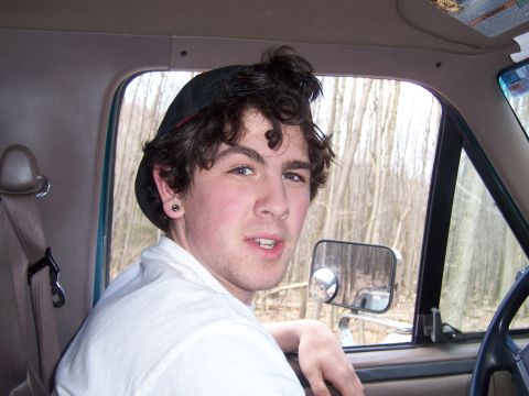 1996 Ford Bronco - A young man with curly hair and a baseball cap looks out from inside a vehicle, with trees visible through the window.