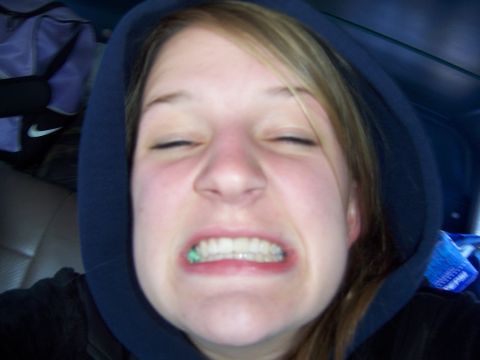 1996 Ford Bronco - A woman makes a funny face while wearing a dark hoodie, with her eyes closed and teeth bared.