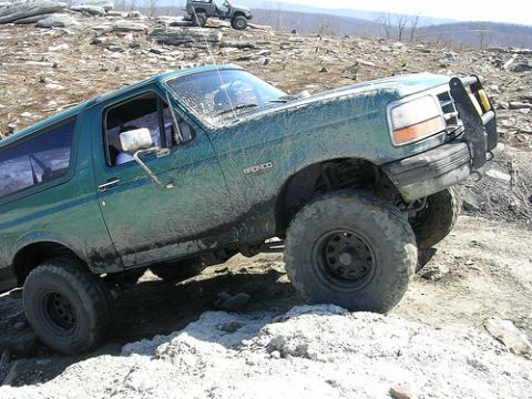 1996 Ford Bronco - Green 1996 Ford Bronco navigating a rocky off-road trail with another vehicle visible in the distance.