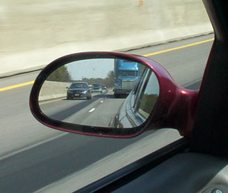 1998 Ford Taurus - Reflection in a car's side mirror shows a highway scene with multiple vehicles.