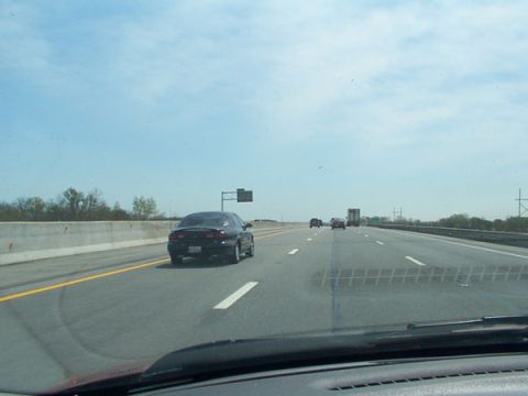 1998 Ford Taurus - A black coupe drives down the highway, seen from behind. The vehicle's body style suggests it is a 1998 model.