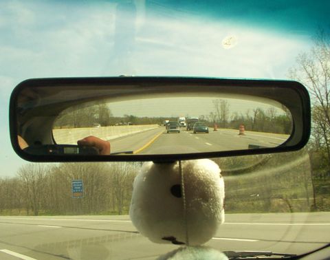 1998 Ford Taurus - View of highway traffic through the rearview mirror, showing other vehicles and the road ahead.