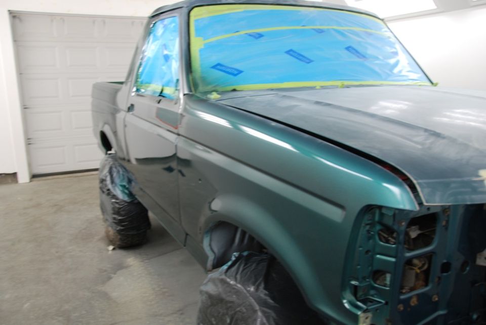 Green Ford pickup truck, front quarter view. Looks like an older model