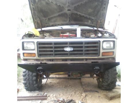 1982 Ford Bronco - Front view of a Ford Bronco with its hood open, an aftermarket bumper and large tires.
