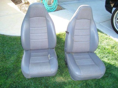 1971 Ford Bronco - Two car seats are shown on a grassy lawn, with a concrete walkway and a green hose in the background.
