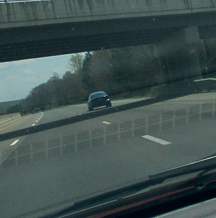 1998 Ford Taurus - A dark sedan travels down the highway, seen from the perspective of another car's windshield.