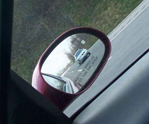 1998 Ford Taurus - Reflection in side mirror shows a car on the road behind. Text on mirror reads 'Objects in mirror are closer than they appear'.