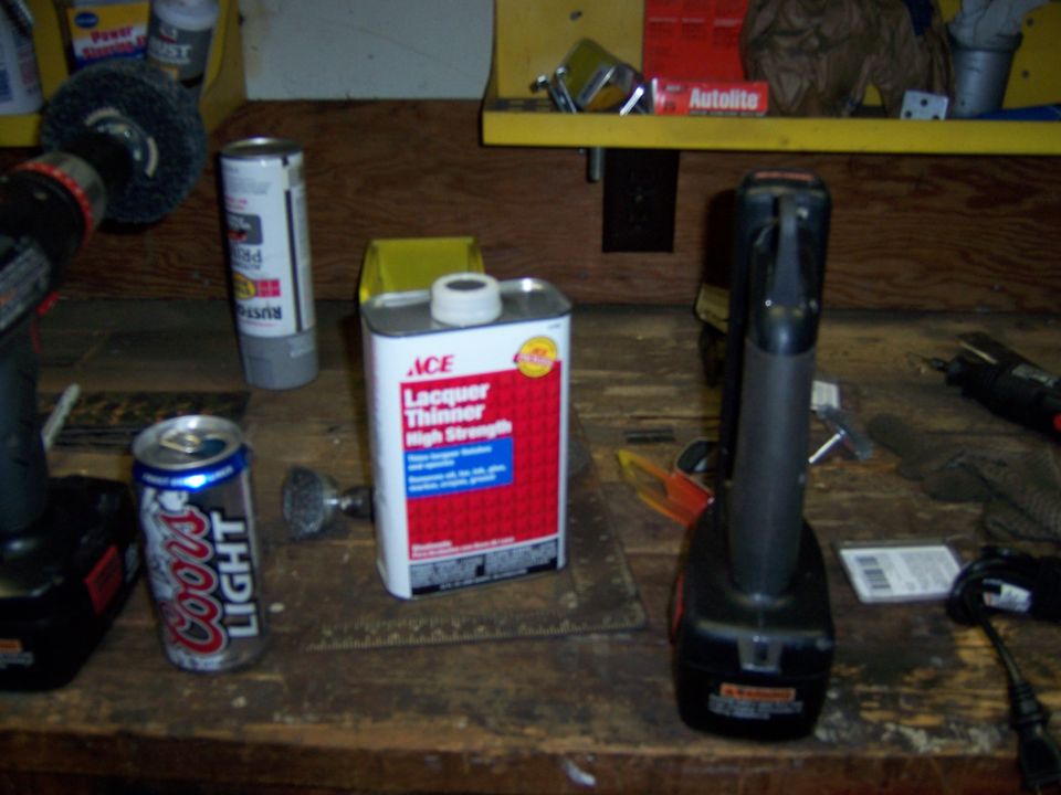 Workbench with two drills, can of Coors Light, can of lacquer thinner, and other supplies