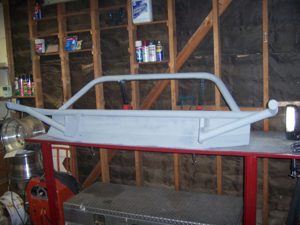 Gray custom front bumper with a brush guard, resting on a red workbench
