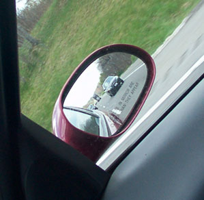 1998 Ford Taurus - Reflection in side mirror shows traffic on the road ahead. Text warns about object proximity.