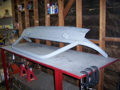1991 Ford Bronco - A custom front bumper, likely for an off-road vehicle, sits on a workbench in a garage.