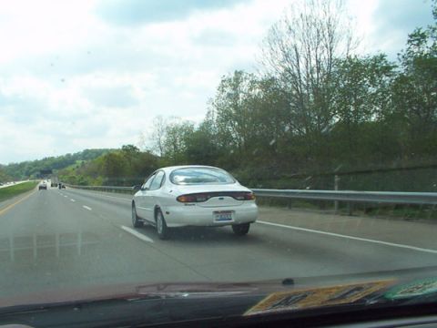 1998 Ford Taurus - A white 1998 Ford Taurus travels down the highway on a cloudy day.