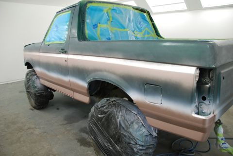 1996 Ford Bronco - A Ford Bronco is prepped for painting, with windows covered and tires protected.