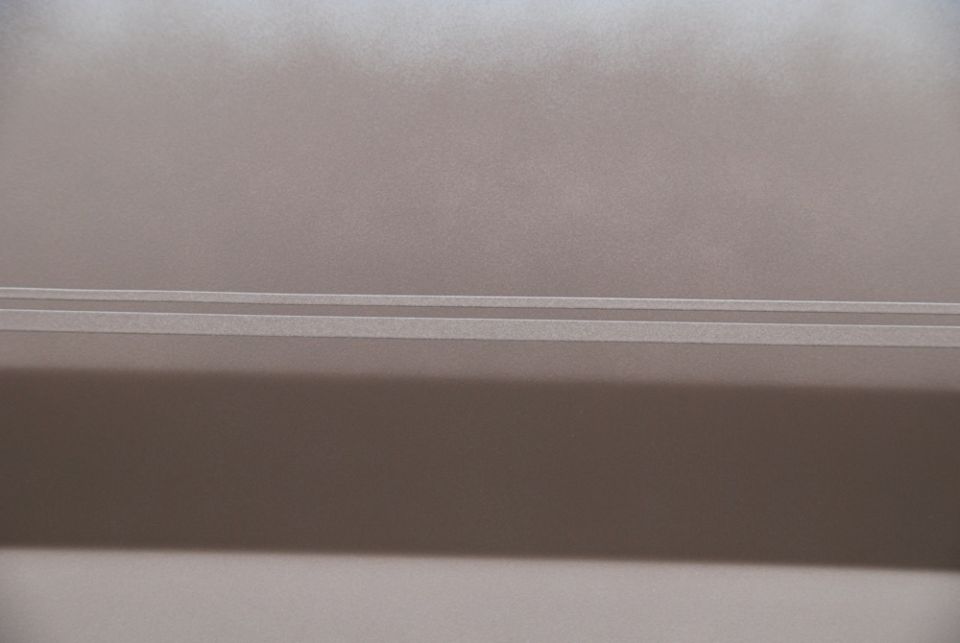 Close-up of a light brown car door with two horizontal trim lines