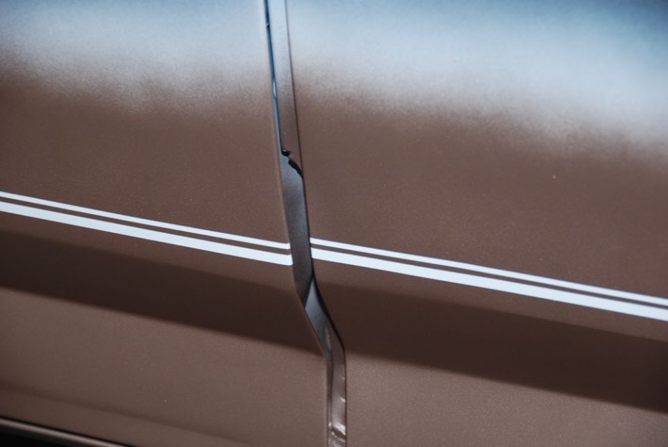 Close-up of a brown car door seam with two white pinstripes