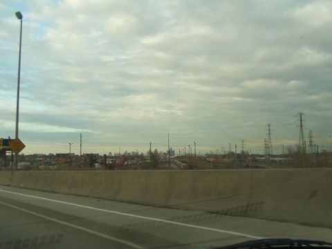 1998 Ford Taurus - A view of a city skyline and industrial area under a cloudy sky, seen from a highway.