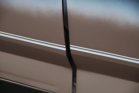 1996 Ford Bronco - A detail shot focuses on the gap between two body panels on a vehicle, accented by thin racing stripes.