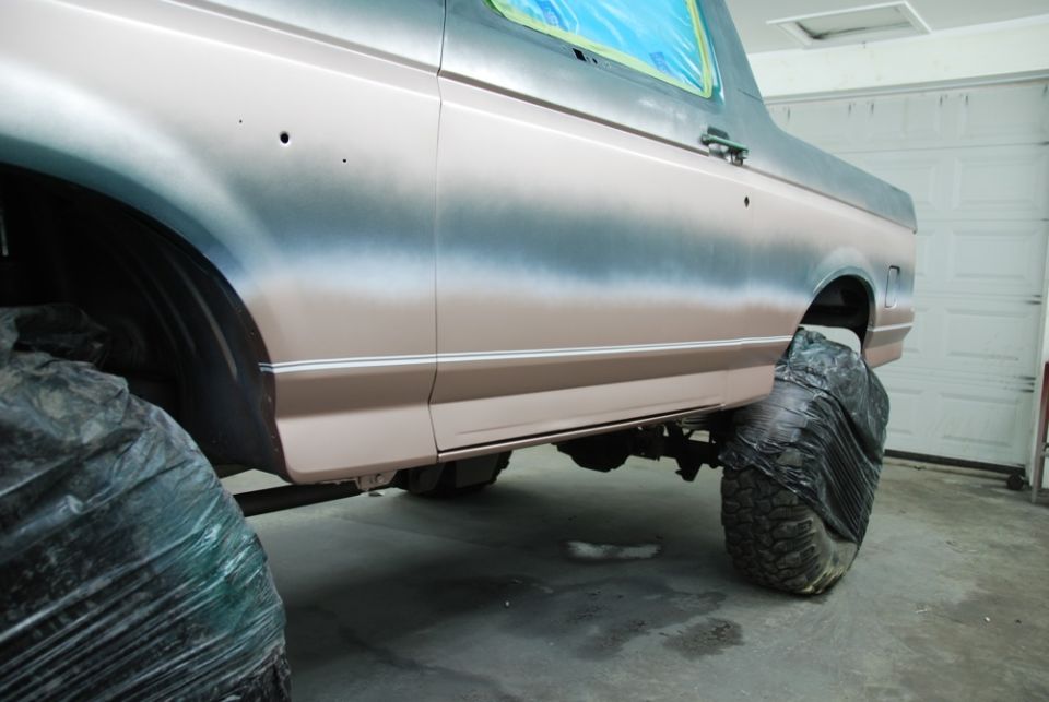 Side view of a vehicle with primer and masking tape, tires covered