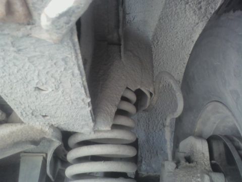 1992 Ford F-350 - Close-up view of the suspension system on a 1992 Ford F-350, revealing a dusty coil spring and surrounding chassis parts.