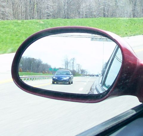 1998 Ford Taurus - Side mirror view of a 1998 Ford Taurus on the highway.