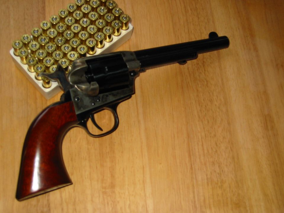 revolver with wooden handle next to a box of bullets
