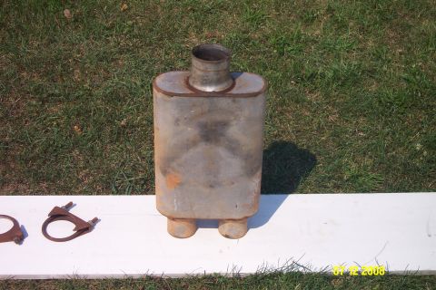 1992 Ford Bronco - Exhaust muffler and two clamps shown on a white surface with grass in the background.