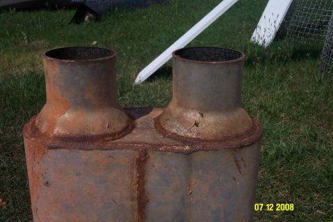 1992 Ford Bronco - This rusty dual exhaust muffler has two pipes and is sitting on grass.