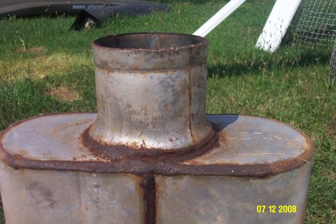 1992 Ford Bronco - This is a close-up of a rusty exhaust muffler with a pipe. Text is visible on the side.