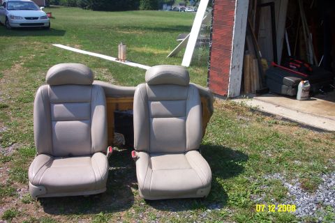 1992 Ford Bronco - Two tan leather car seats are displayed outdoors next to a garage.