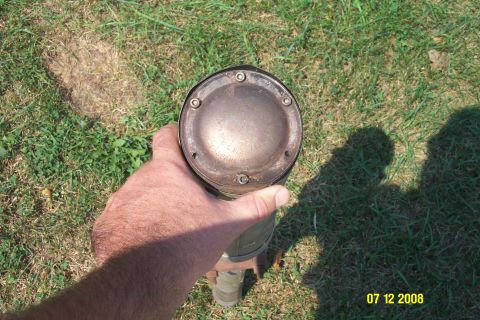 1992 Ford Bronco - A person holds a used exhaust muffler outdoors, with grass and shadows visible in the background.