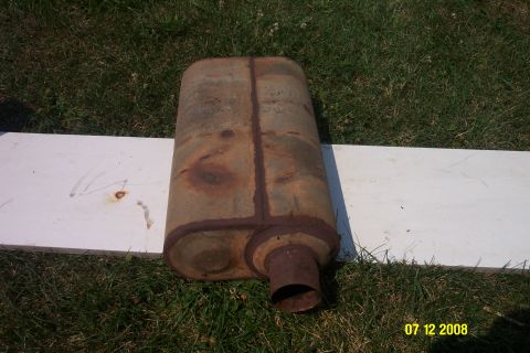 1992 Ford Bronco - A heavily rusted exhaust muffler is shown outdoors on a grassy area, placed on a white board.