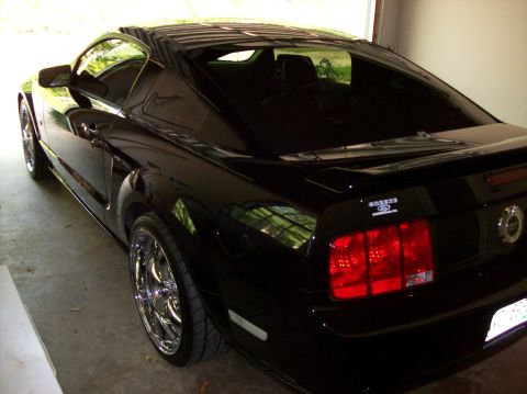 2007 Ford Mustang - Rear three-quarter view of a black Ford Mustang coupe with aftermarket chrome wheels.