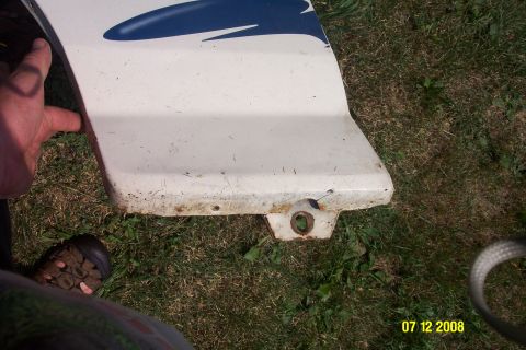 1992 Ford Bronco - Close-up of a white vehicle fender with a blue graphic, exhibiting rust along the bottom edge.
