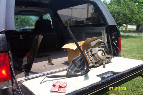 1992 Ford Bronco - The interior of a black 1992 Ford Bronco is visible with the tailgate open, revealing disassembled parts including a headlight assembly.