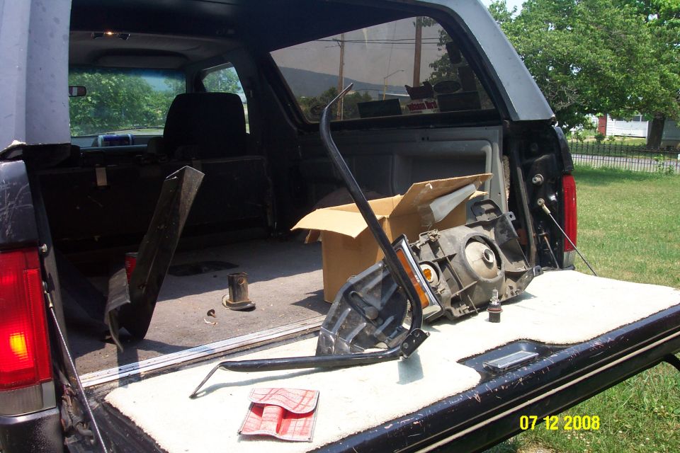 Open rear cargo of dark Ford Bronco with headlamp and parts on tailgate