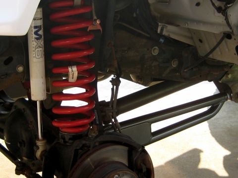 1996 Ford Bronco - Close-up of a vehicle's front suspension system, showing a red coil spring and shock absorber.