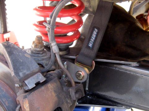 1996 Ford Bronco - A close-up view of a vehicle's suspension system, highlighting a FABTECH strap and red coil spring.