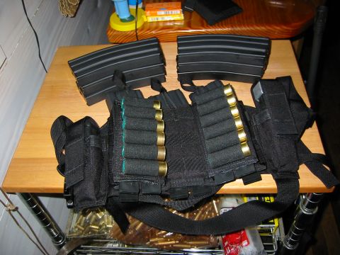 1996 Ford Bronco - A tactical vest is laid out on a wooden surface, holding rifle magazines and shotgun shells, with more ammunition visible underneath.