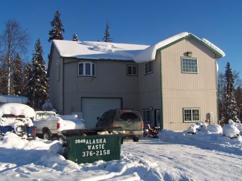 1989 Ford Bronco II - Winter scene with a building, dumpster, and vehicles covered in snow.